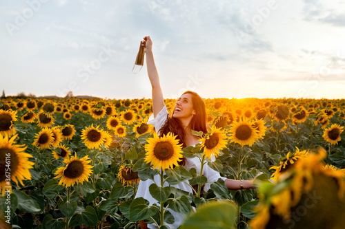 Woman among sunflowers with face mask on something at sunset