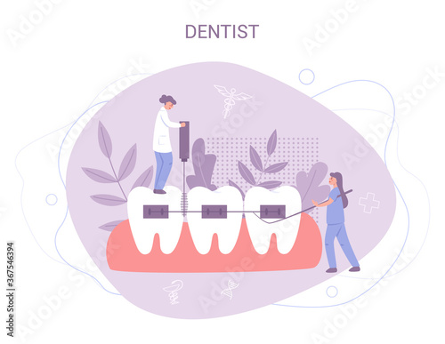 Group of small dentists in uniform treat giant tooth using medical photo