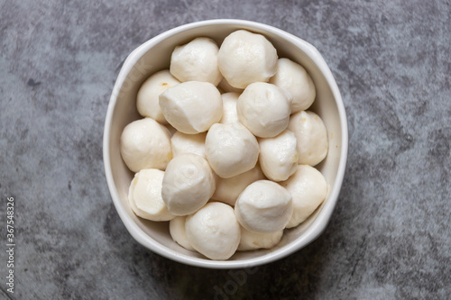 Boiled fish balls in white bowl on black marble table with copy space; top view