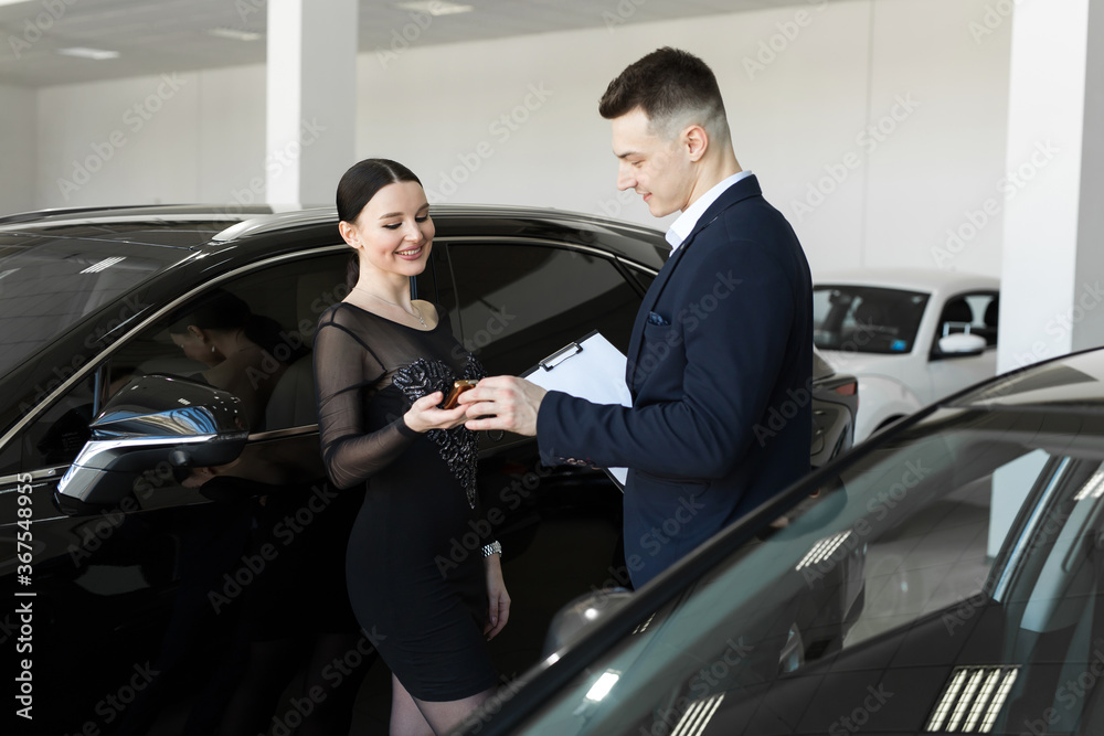 Seller gives the buyer the keys to a new car in the showroom Seller gives the buyer the keys to a new car in the showroom