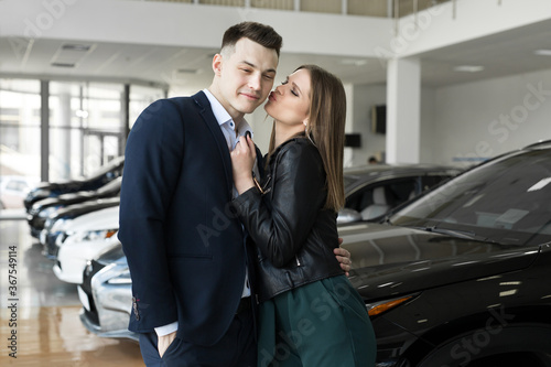 A couple of men and women are happy to buy a new car in a car dealership