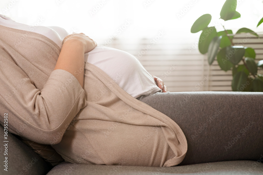 Portrait shot of young beautiful woman on third trimester of pregnancy. Close up of pregnant female with arms on her round belly. Expecting a child concept. Background, copy space. Portrait shot of young beautiful woman on third trimester of pregnancy. Close up of pregnant female with arms on her round belly. Expecting a child concept. Background, copy space.
