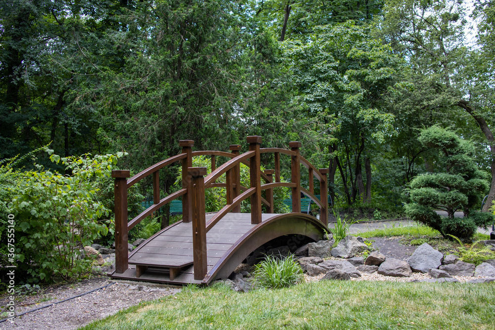 Landscaped park with green trees and an asian style bridge. Landscaped park with green trees and an asian style bridge.