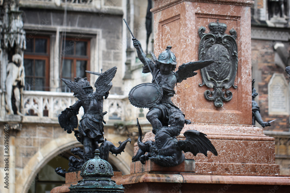 Close-up ancient statue of Putto killing devil at the Marian column's pedestal Marienplatz, Munich, Germany, travel destination backgrounds