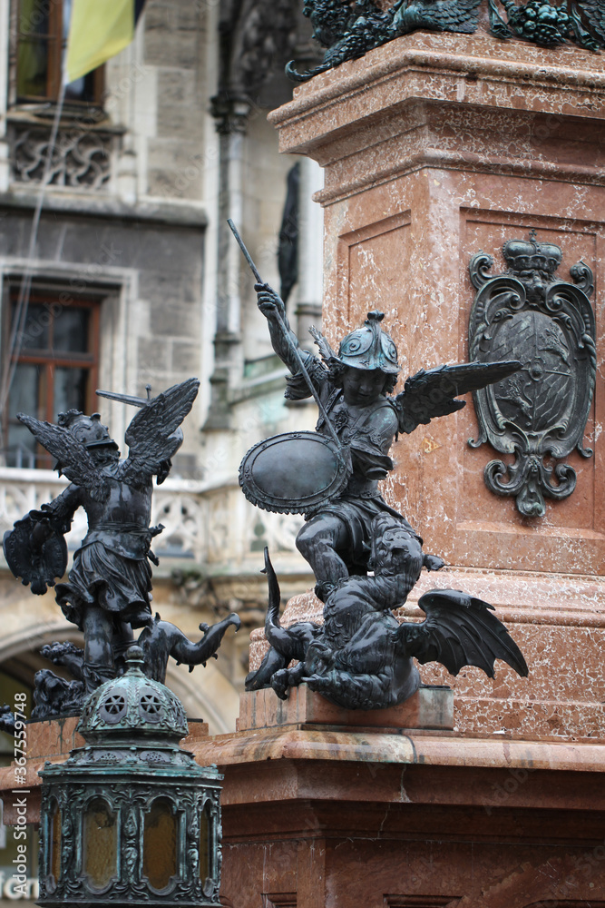 Close-up ancient statue of Putto killing devil at the Marian column's pedestal Marienplatz, Munich, Germany, travel destination backgrounds