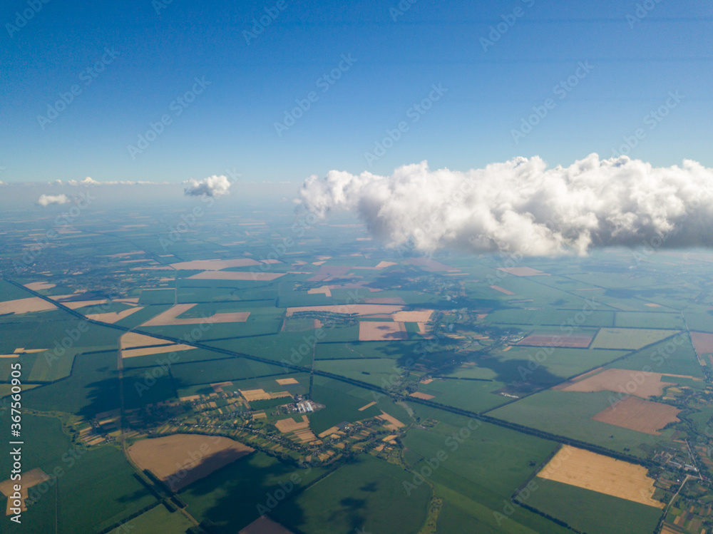 Flying in the clouds over the agricultural fields of Ukraine. Aerial flight.