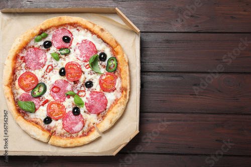 Delicious pizza Diablo in cardboard box on wooden background, top view. Space for text