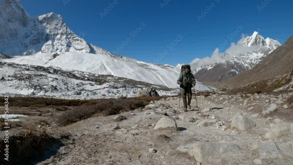 Tourist - Hiker walking up the footpath on the Everest Base Camp trek in the Himalaya, Nepal. Himalaya landscape and mountain views. Tourist - Hiker walking up the footpath on the Everest Base Camp trek in the Himalaya, Nepal. Himalaya landscape and mountain views.