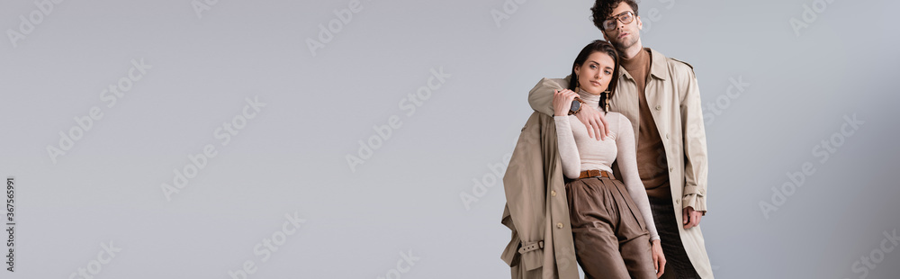 © LIGHTFIELD STUDIOS - panoramic shot of trendy man embracing fashionable woman while looking at camera isolated on grey © LIGHTFIELD STUDIOS - panoramic shot of trendy man embracing fashionable woman while looking at camera isolated on grey