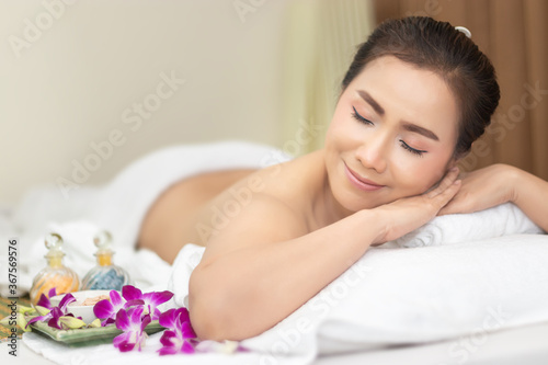 portrait of beautiful young Asian woman naked back, lay down on massage bed with relaxing felling at beauty spa treatment. relaxing massage. advertising poster