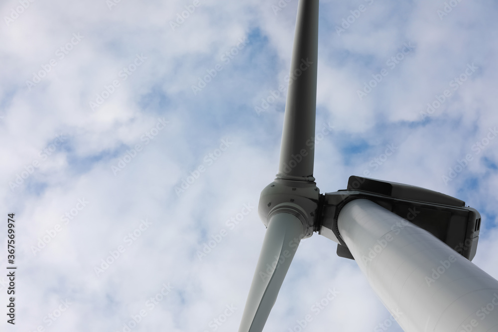 Wind turbine against cloudy sky, low angle view. Alternative energy source Wind turbine against cloudy sky, low angle view. Alternative energy source