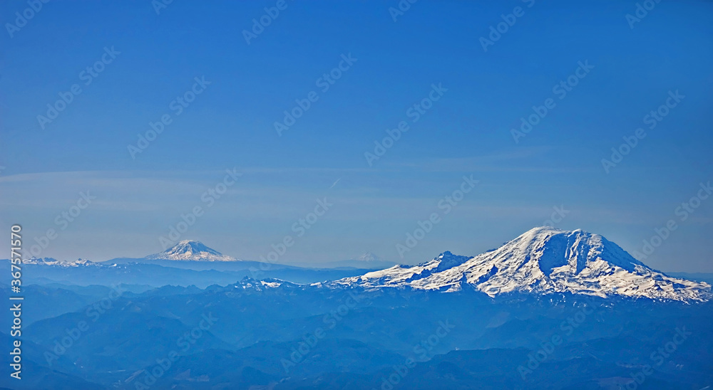 This aerial photo is of Mount Rainier in the foreground and in the background is also Mount St. Helens, both volcanoes in Washington state.