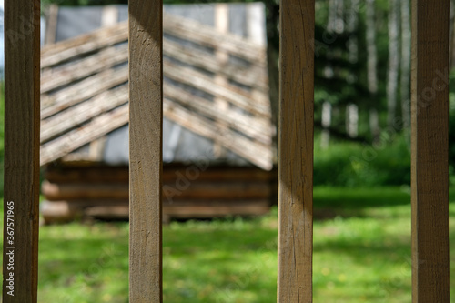 Close-up: a view of the garden with a gazebo, which stands on a lawn with green grass, through a picket fence at large intervals.