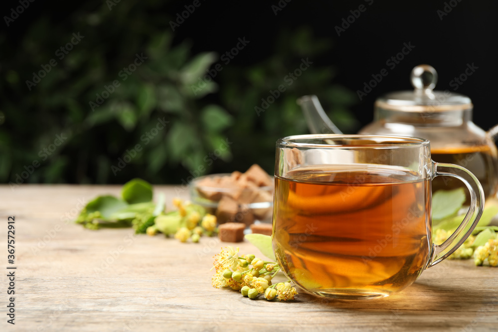 Cup of tea and linden blossom on wooden table. Space for text Cup of tea and linden blossom on wooden table. Space for text