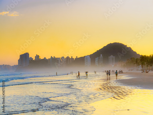 Enseada beach in Brazil during dusk: people enjoying a warm summer day in a beautiful seaside town. photo