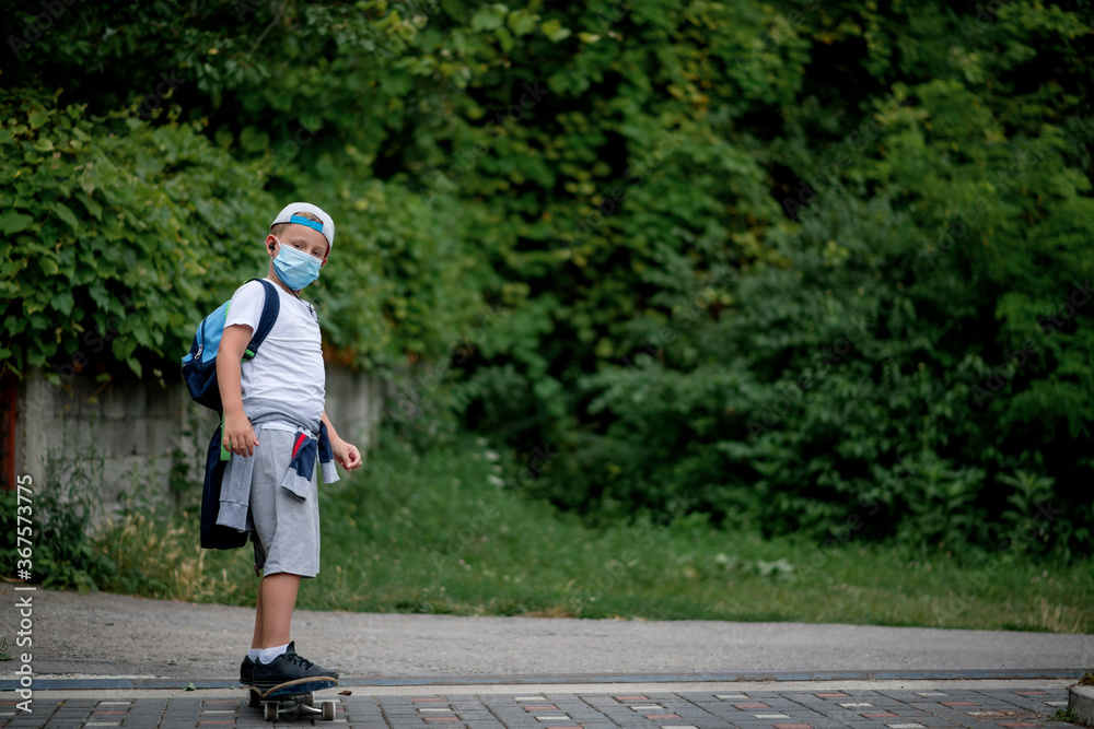 Fototapeta premium Caucasian boy riding a skateboard, wearing a protective face mask