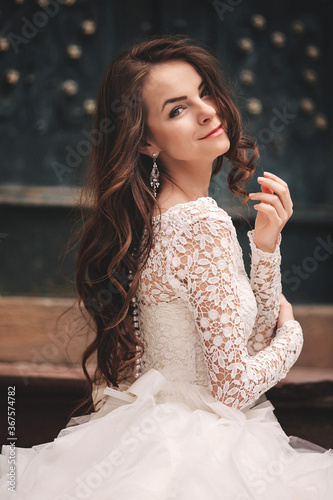 portrait of a beautiful young bride in a white wedding dress with long hair in the old European city. Woman near old building. wedding day