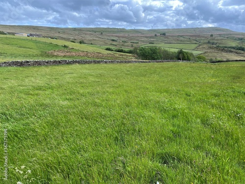 Large open landscape, with meadows, fields, dry stone walls, rising to the hills, above Denholme, Bradford, UK