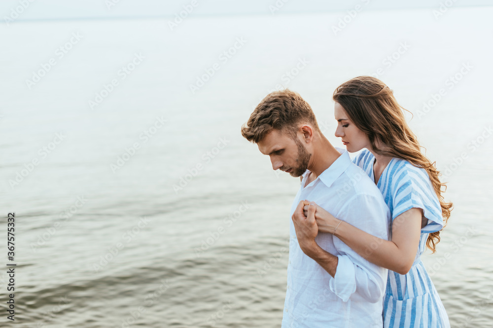 attractive woman hugging handsome boyfriend near river