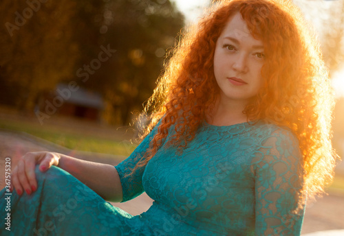 portrait of a young woman with red hair in the background of the sun