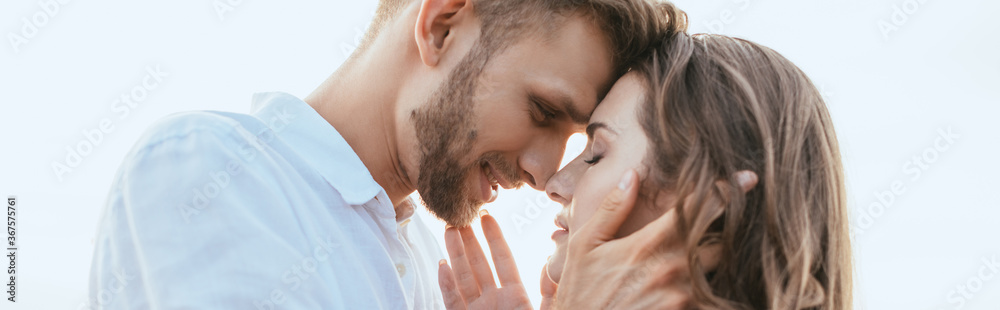panoramic crop of handsome and bearded man touching face of beautiful girlfriend outside panoramic crop of handsome and bearded man touching face of beautiful girlfriend outside