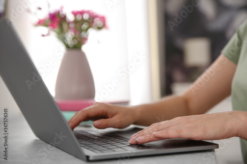 Woman working with modern laptop at light table, closeup