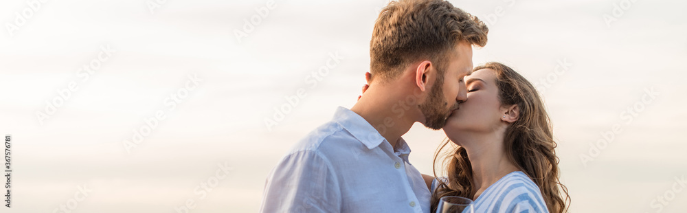 panoramic shot of bearded man kissing girlfriend outside panoramic shot of bearded man kissing girlfriend outside