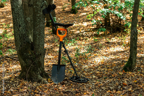shovel with a metal detector under a tree in the forest