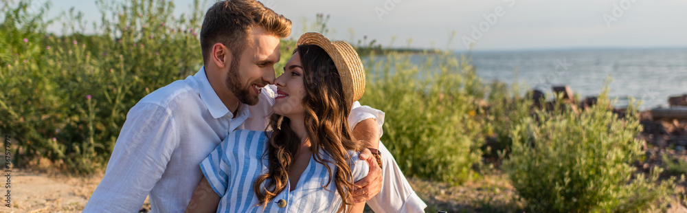 panoramic shot of bearded man looking at happy young woman in straw hat panoramic shot of bearded man looking at happy young woman in straw hat