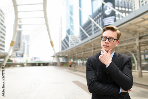 Young handsome blond businessman thinking in the city outdoors