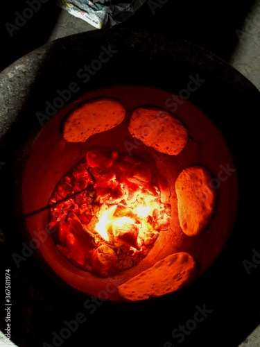 Fotografie Roti and Naans getting cooked in an Indian oven  called Tandoor