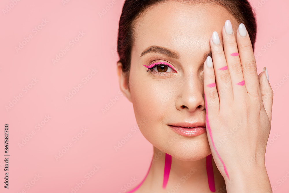 beautiful woman with pink lines on body covering face with hand isolated on pink