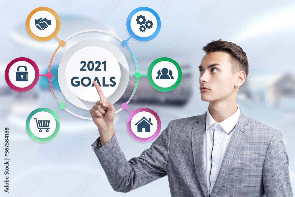 Business, Technology, Internet and network concept. Young businessman working on a virtual screen of the future and sees the inscription: 2021 goals Business, Technology, Internet and network concept. Young businessman working on a virtual screen of the future and sees the inscription: 2021 goals