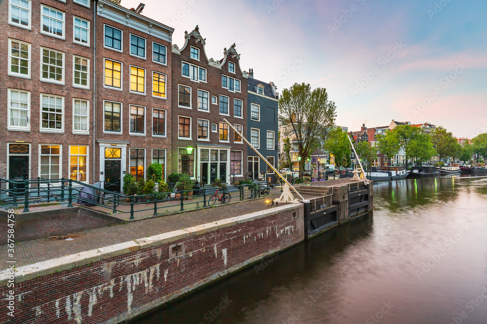 Naklejka premium Amsterdam streets, canals during dusk on the Sint Antoniesluis