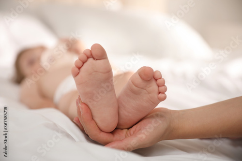 Orthopedist examining little baby on bed, closeup