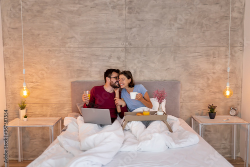 Couple drinking coffee and having breakfast in bed