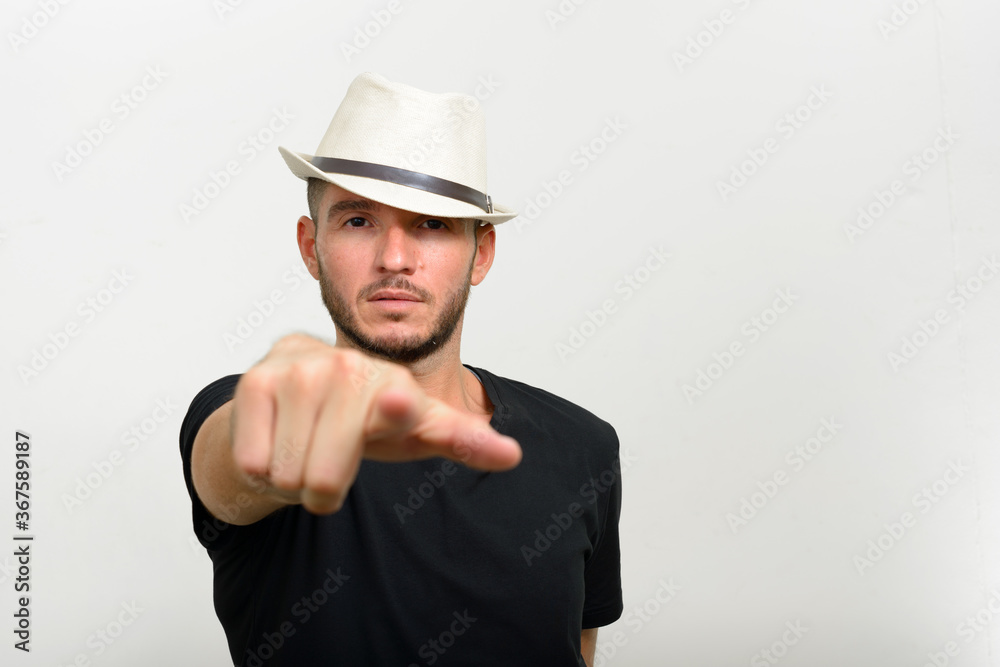 Studio shot of handsome bearded Hispanic man wearing hat Studio shot of handsome bearded Hispanic man wearing hat