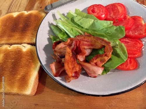 All the disparate parts of a BLT Sandwich, Toasted white bread, fresh tomato, fresh lettuce, and fried bacon, waiting for assembly