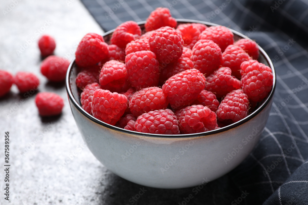 Delicious fresh ripe raspberries in bowl on grey table, closeup Delicious fresh ripe raspberries in bowl on grey table, closeup