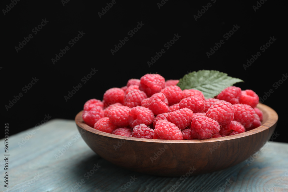 Delicious fresh ripe raspberries in plate on blue wooden table Delicious fresh ripe raspberries in plate on blue wooden table