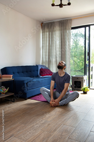 A young man doing butterfly sit-ups in the living room of his tiny appartment during pandemic lockdown © Bruno Daniel