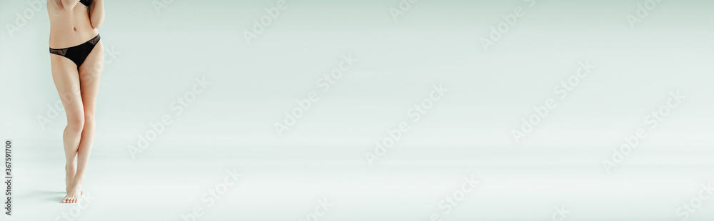 Cropped view of woman in black panties standing on grey background Cropped view of woman in black panties standing on grey background