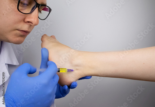 Foto An orthopedic surgeon injects medicine into the Achilles tendon to relieve pain