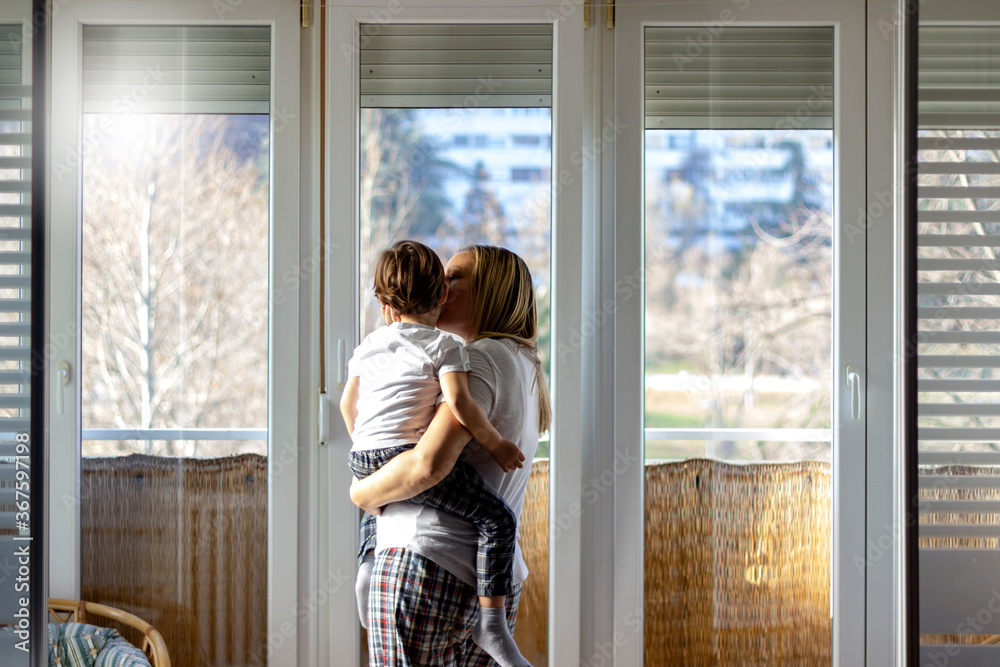 Young single mother hugging and playing with her little son at home.Happy family,mother and son toddler laughing and hugging on the balcony at home.Shot of adorable boy affectionately kissing mother. Young single mother hugging and playing with her little son at home.Happy family,mother and son toddler laughing and hugging on the balcony at home.Shot of adorable boy affectionately kissing mother.