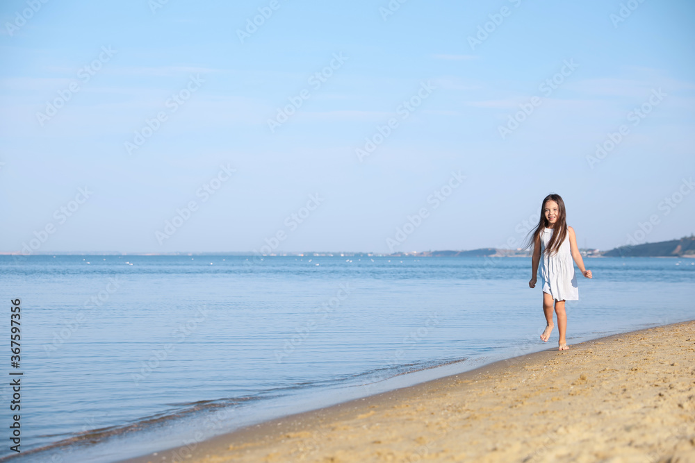 Cute little child running at sandy beach on sunny day