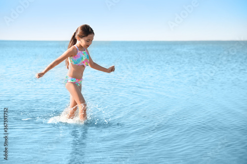 Cute little child having fun in sea on sunny day. Beach holiday