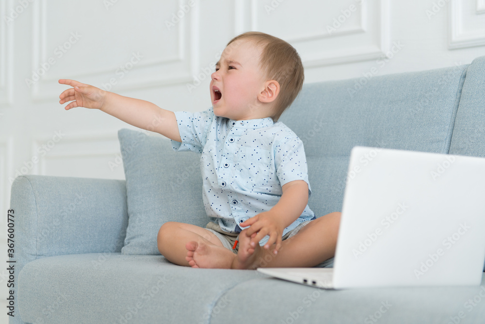 sad baby crying near laptop - tantrum child on sofa