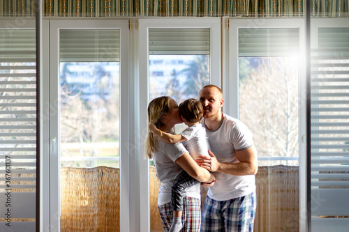 Happy family having fun together.Married couple enjoy having fun time with cute little son at home.Family weekend with child.Shot of young father kissing and cuddle his wife and their sweet little son © Jelena Stanojkovic