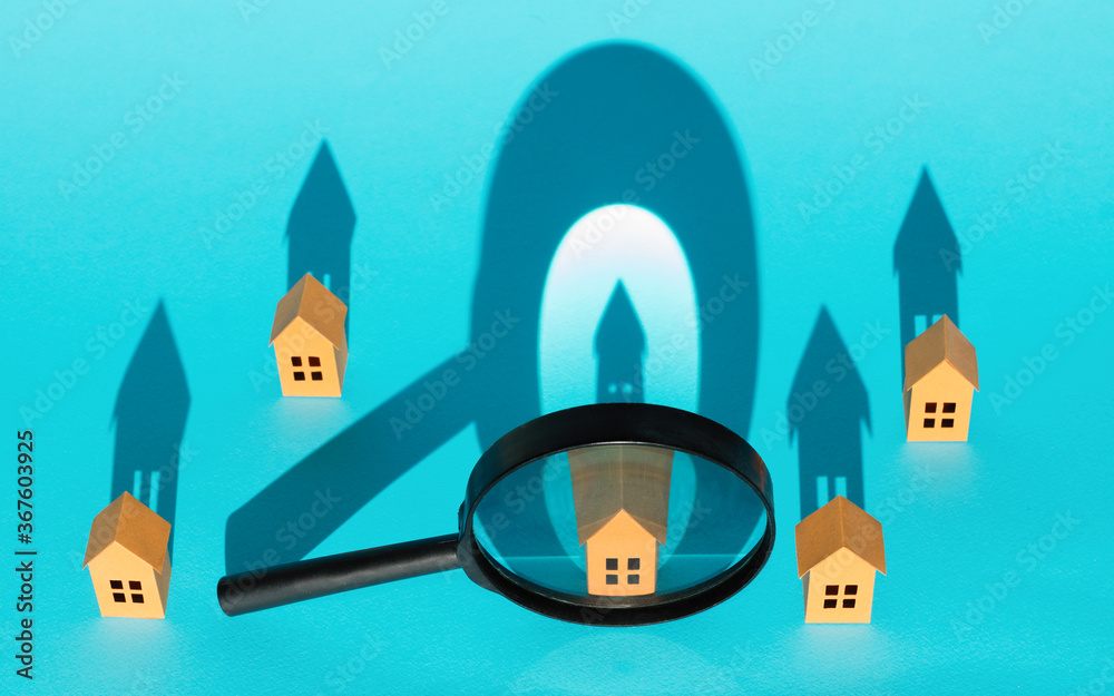 Magnifier in front of paper houses on blue background. Concept of rent, search, purchase real estate. Magnifier in front of paper houses on blue background. Concept of rent, search, purchase real estate.
