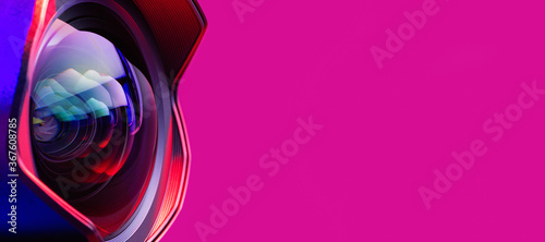 .Banner. The camera lens with bright pink and blue  backlight. Close-up of the camera lens on a red  background. Optics. photo